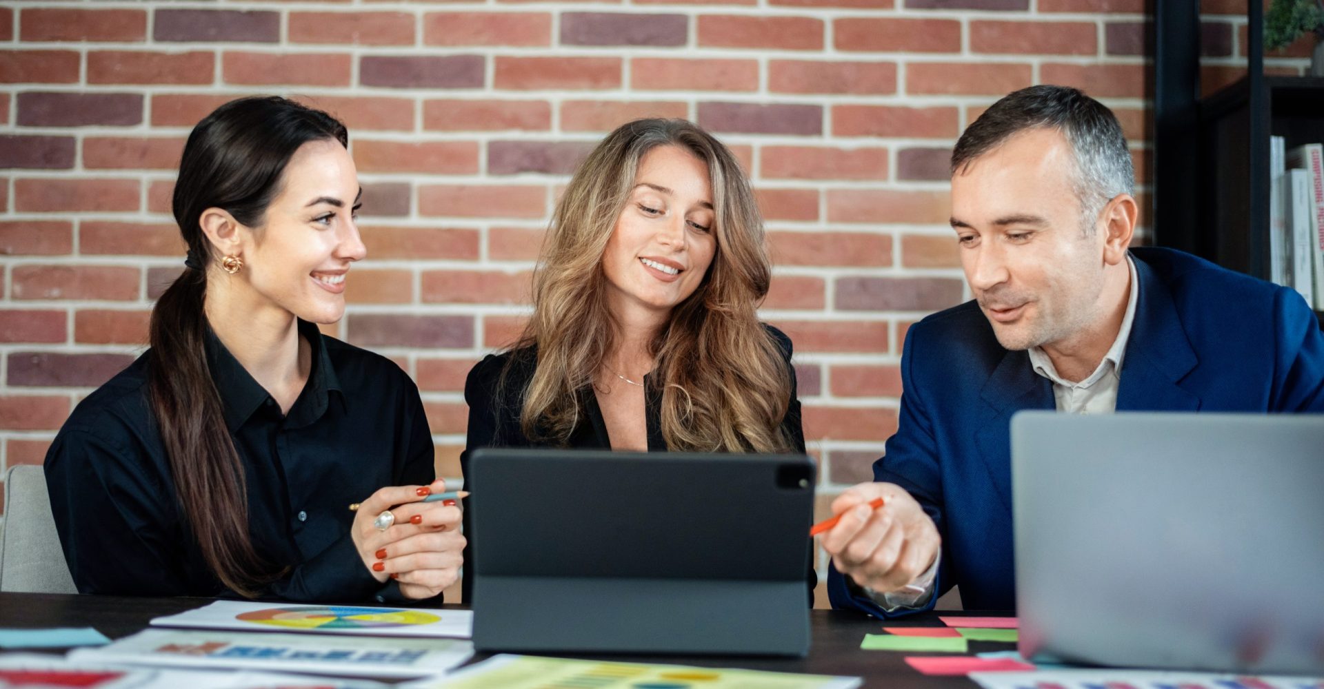 Business session in an office. Women and a man discussing business affairs. Gadgets and papers with graphs and notes